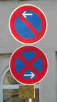 Two road signs, one with a slashed circle and an arrow pointing left, and one with a double-slashed circle and an arrow pointing right