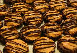Chocolate cookies topped with peanut butter and stripes of chocolate
