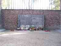 Brick wall with flowers and candles on the ground in front of a stone segment