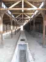 Shell of a wooden building with a stone trough running down the center